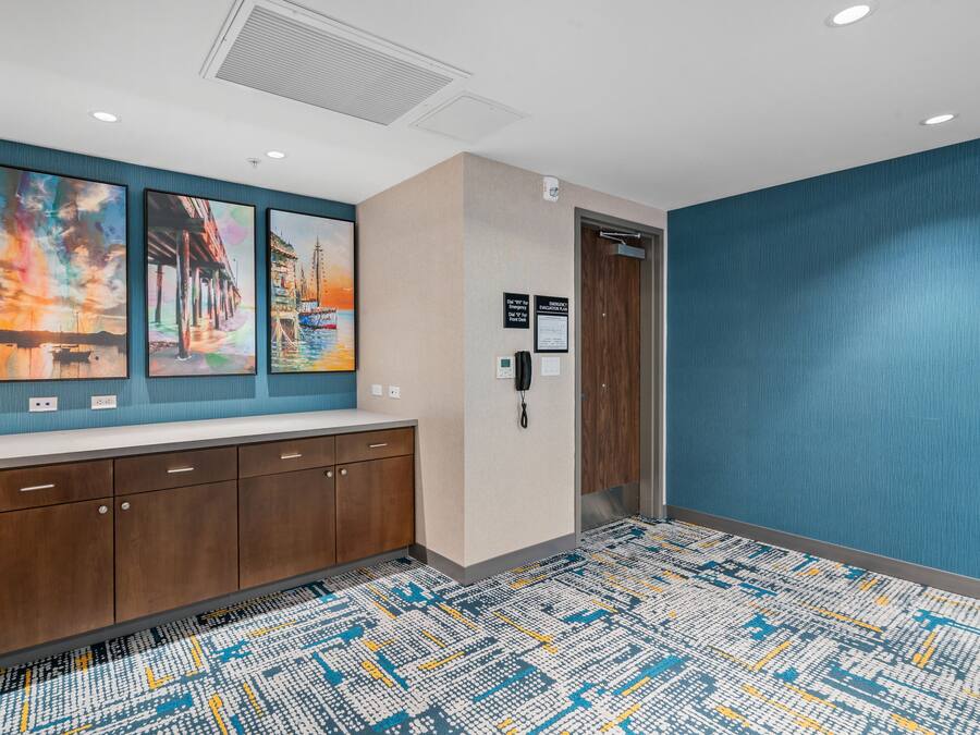 A hotel lobby with a reception desk, artwork on the wall, a patterned carpet, and a blue accent wall.