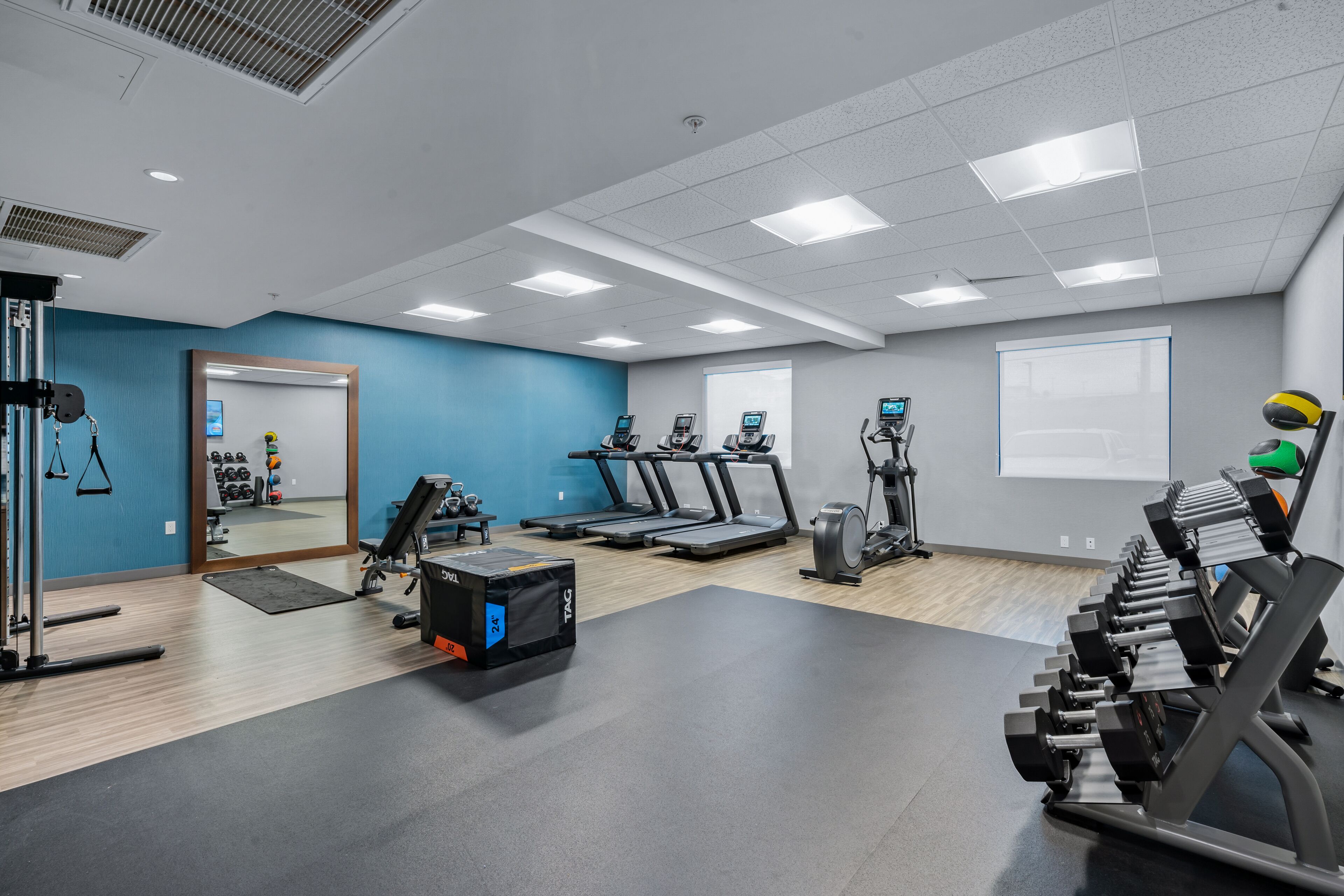 Une salle de sport équipée de tapis de course, d’appareils de musculation et d’un miroir.