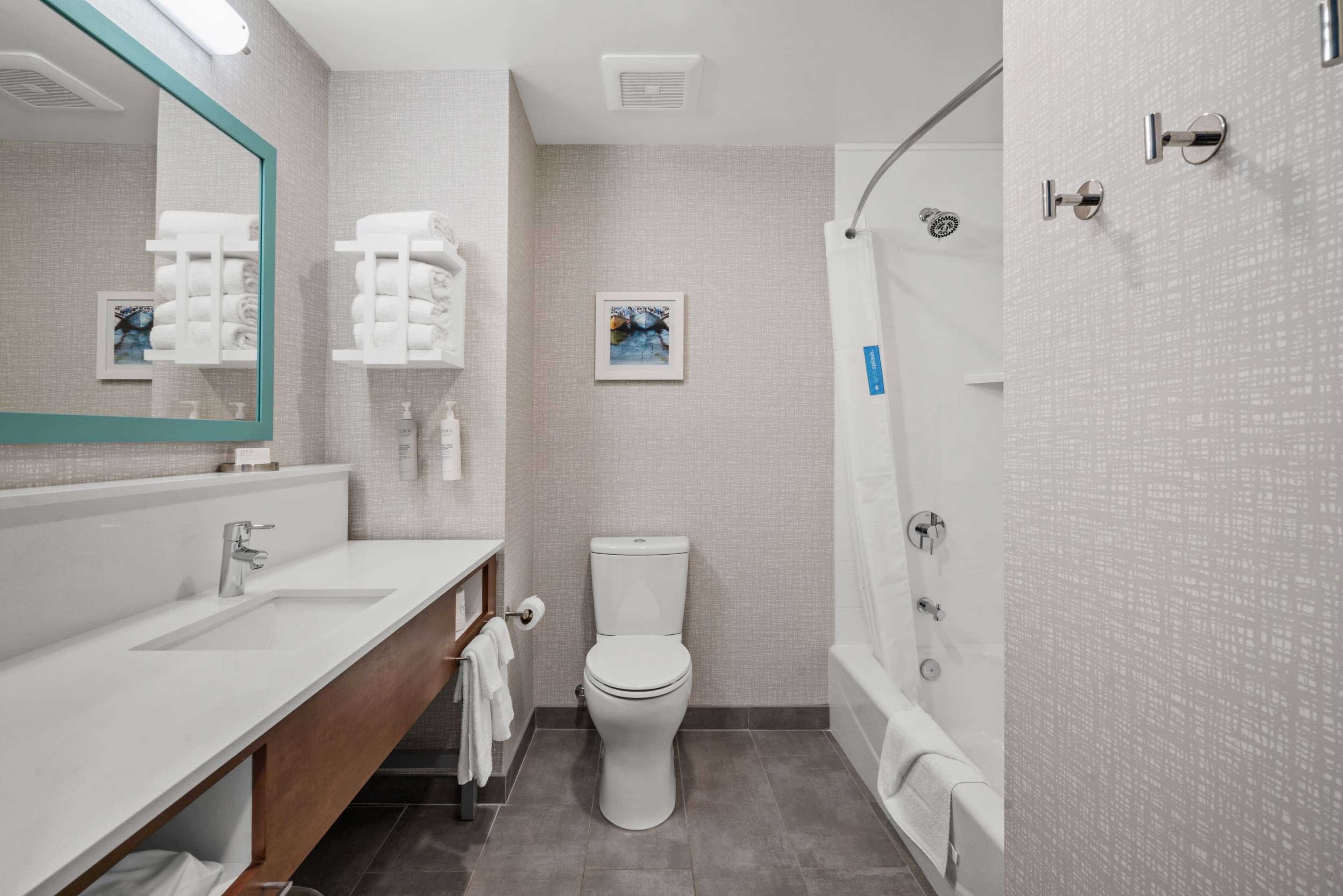 A modern bathroom with a white sink, a toilet, and a shower.
