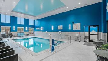 A modern indoor pool area with clear signage, a lifeguard station, and seating areas.