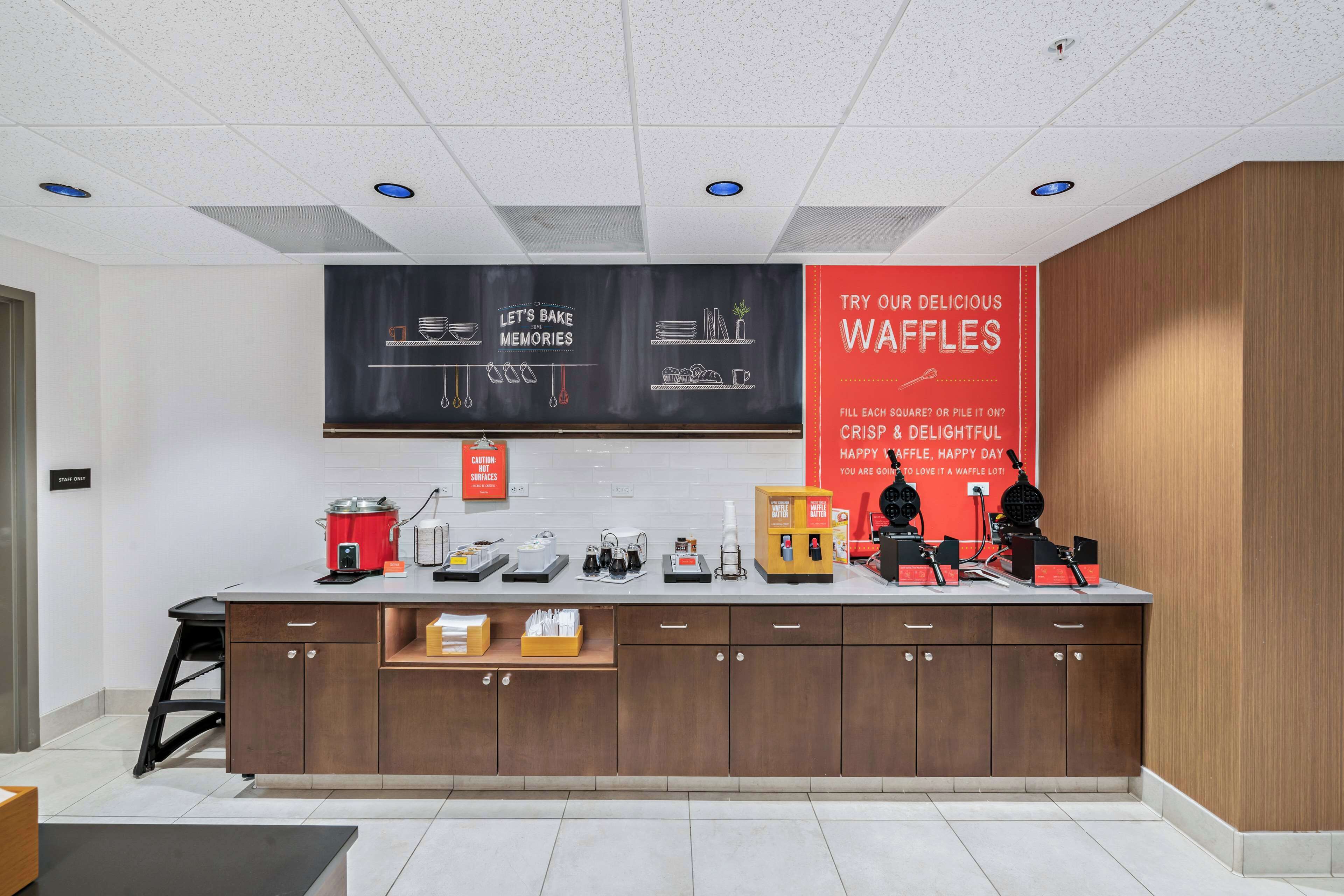 A modern kitchen with a large island, various appliances, and a waffle station.
