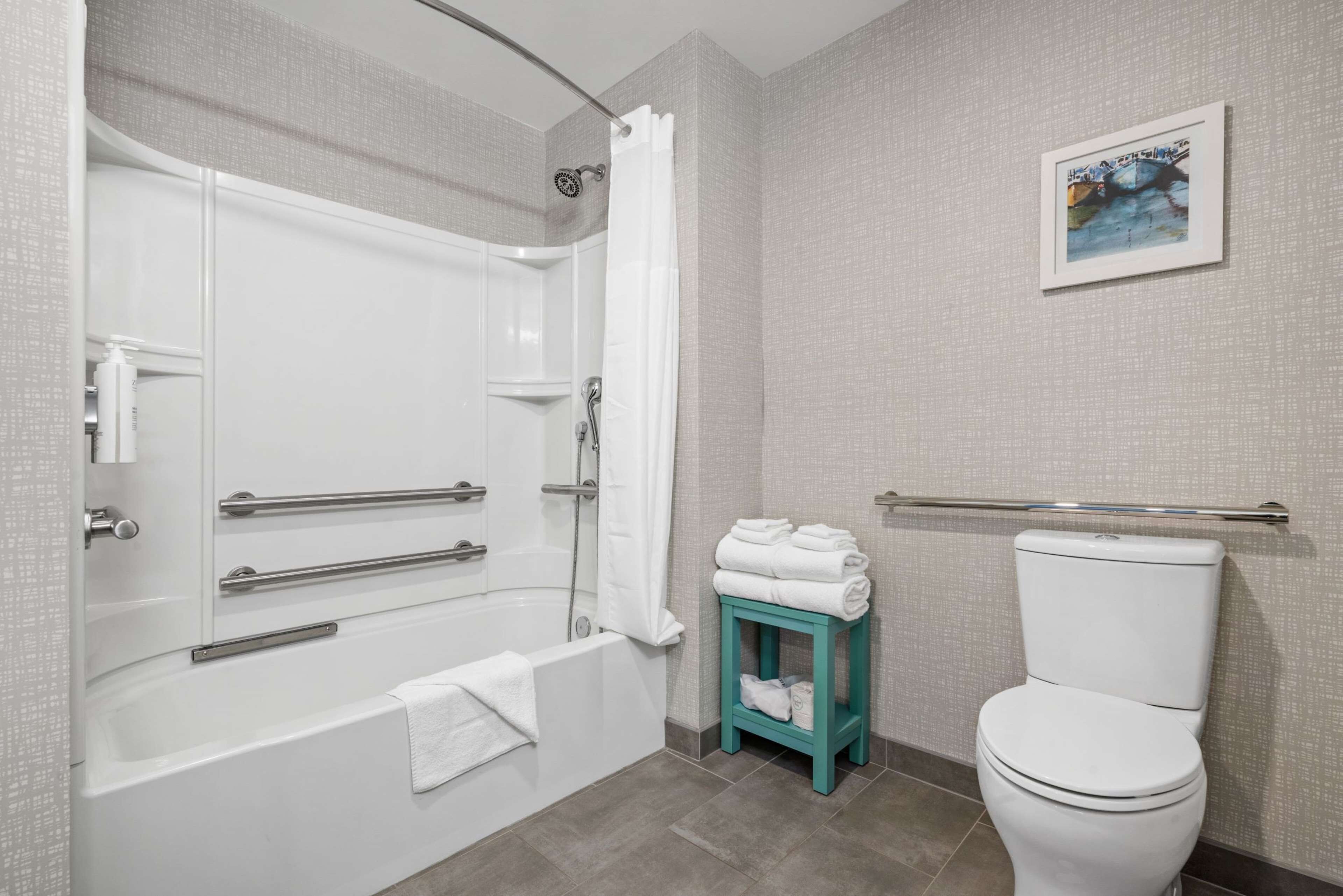 A bathroom with a bathtub, toilet, and a small table with towels.