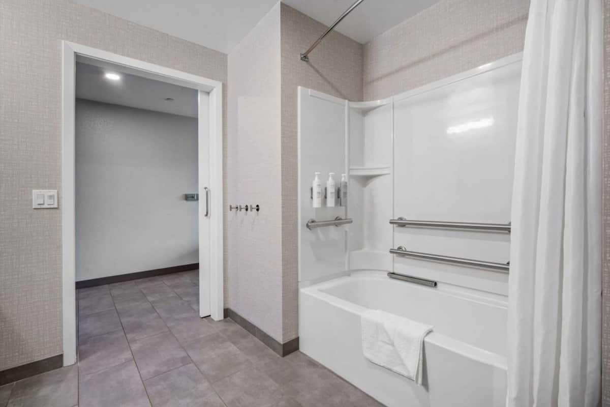 A modern bathroom with a walk-in shower, a bathtub, and a towel rack.