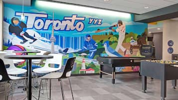 A room with a mural of Toronto, a foosball table, and a piano.