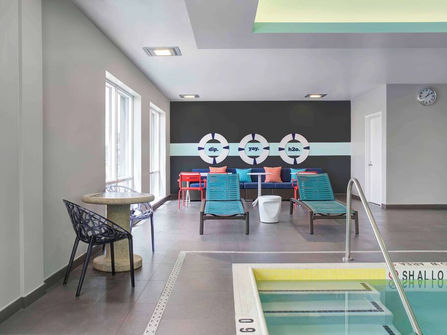 Un área de piscina con sillones, una mesa y una pared con diseños circulares.
