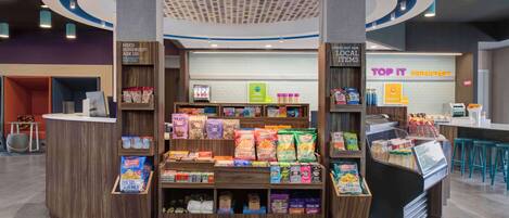 A 24/7 market with a variety of food and drink options, including a breakfast area and a juice bar.