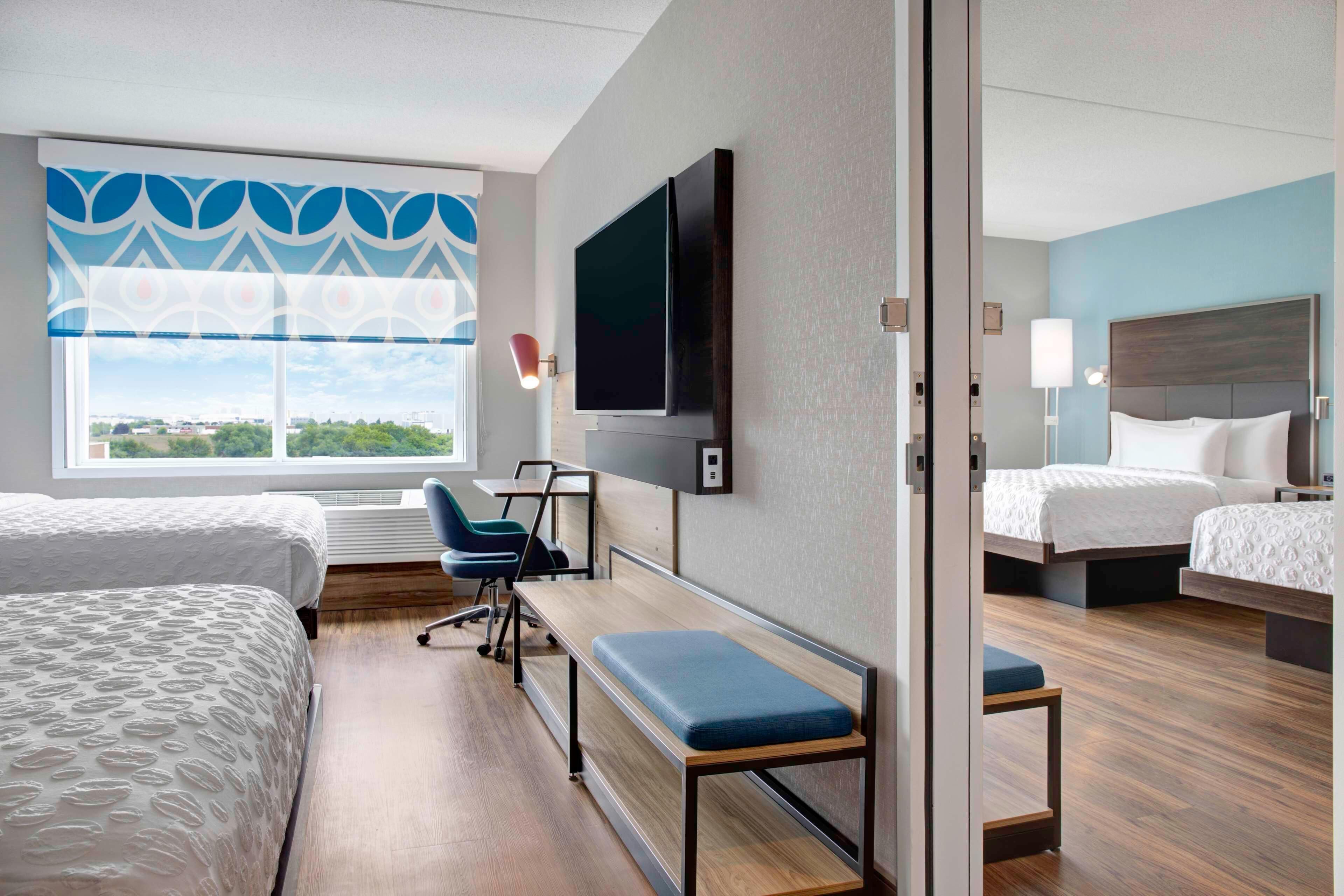 Une chambre d’hôtel avec deux lits, une télévision, un bureau et une vue sur la ville.