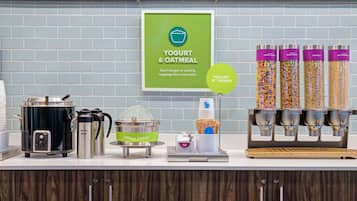 A yogurt and oatmeal station with dispensers, a coffee maker, and a sign encouraging creative toppings.