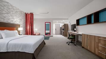 A hotel room with a large bed, a desk, a chair, and a TV.