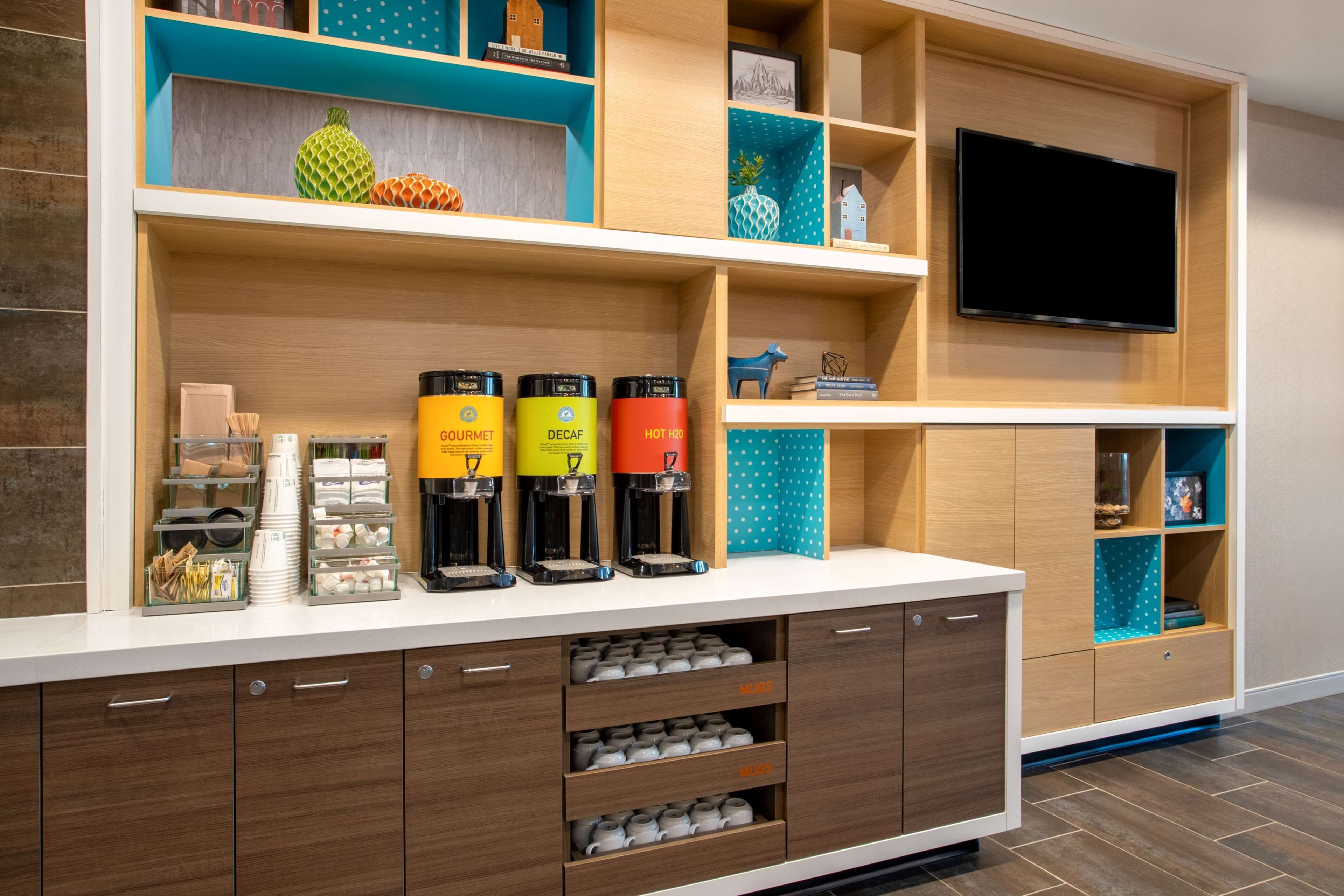A modern kitchen area with built-in appliances, a coffee station, and a flat-screen TV.