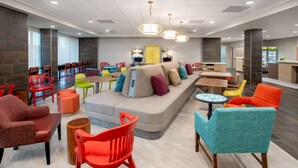 A modern lounge area with a large seating area, multiple tables, and colorful chairs. - Home2 Suites By Hilton Calhoun (Calhoun)