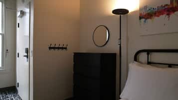 Een slaapkamer met een bed, een kaptafel, een spiegel en een kapstok.