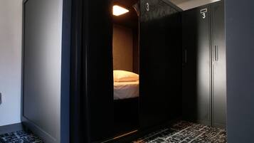 A compact room with a bed, a wardrobe, and a patterned floor.