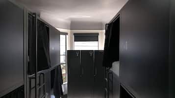 Un estrecho pasillo con literas, una ventana con persianas y una puerta con el número.