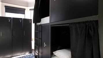 A room with bunk beds, numbered lockers, and a window with a view.
