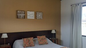 Une chambre à coucher comprenant un lit, deux tables de chevet, une lampe et trois œuvres d’art murales.