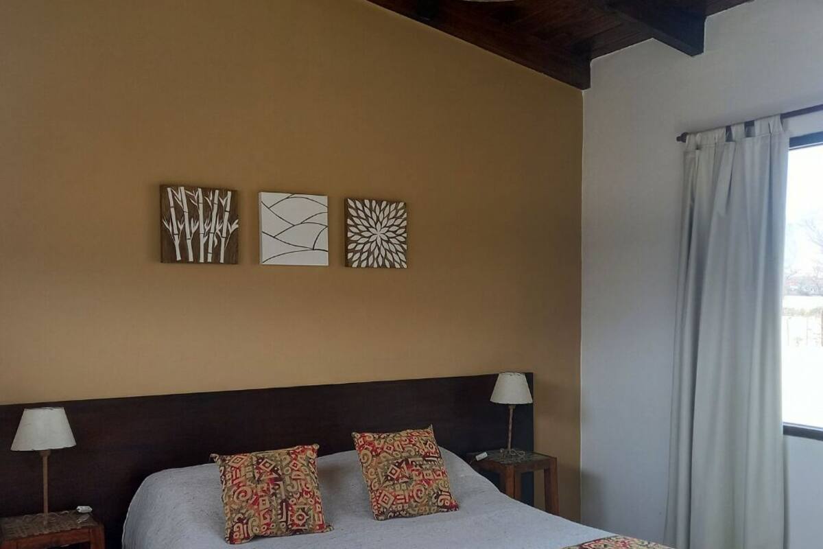 Une chambre à coucher comprenant un lit, deux tables de chevet, une lampe et trois œuvres d’art murales.