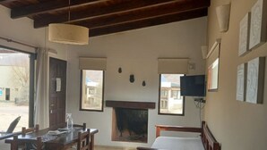 Une pièce avec un plafond en bois, une cheminée, un lit, une table avec des chaises et un téléviseur.