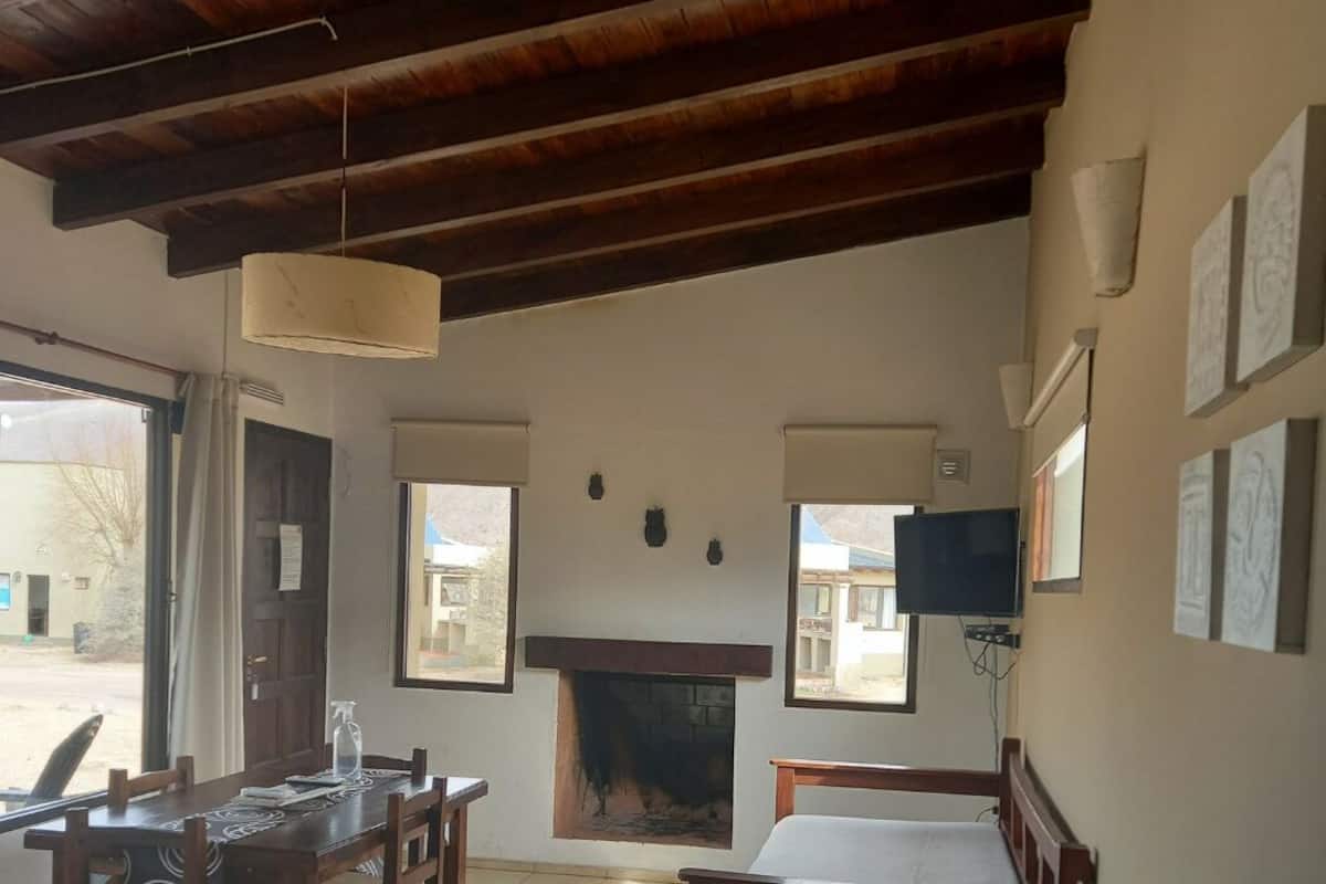 Une pièce avec un plafond en bois, une cheminée, un lit, une table avec des chaises et un téléviseur.