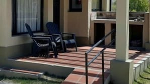 Un espace patio aménagé avec deux chaises, une petite table et un barbecue.
