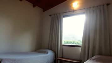 A room with a bed, a small table, and a window with curtains.