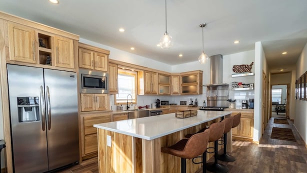 A modern kitchen with wooden cabinets, stainless steel appliances, and a central island with bar stools.