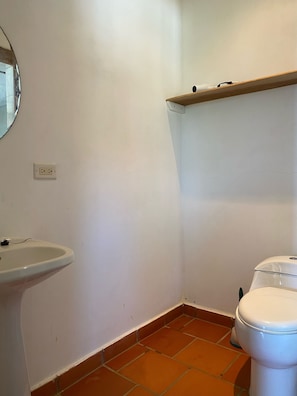 Une petite salle de bain avec un lavabo blanc, des toilettes et un miroir au mur.
