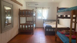 A room with bunk beds, a mirror, a window with curtains, and an air conditioning unit. - Relaxed house in Well located, Authentic, tranquil and unspoilt fishing village. (Tonosi)
