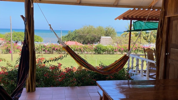 A covered patio with a hammock, a wooden table, and a view of the ocean and garden. - Relaxed house in Well located, Authentic, tranquil and unspoilt fishing village. (Tonosi)