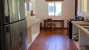 A kitchen with a refrigerator, stove, and tiled floor. - Relaxed house in Well located, Authentic, tranquil and unspoilt fishing village. (Tonosi)