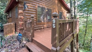 Une cabane en rondins avec une terrasse en bois et une plaque portant le numéro « 95 ».