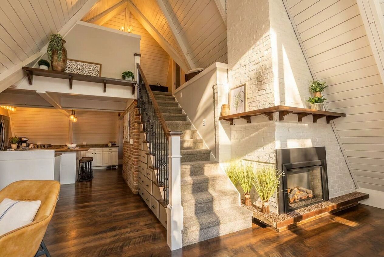 A spacious loft with a fireplace, wooden floors, and a kitchen area.