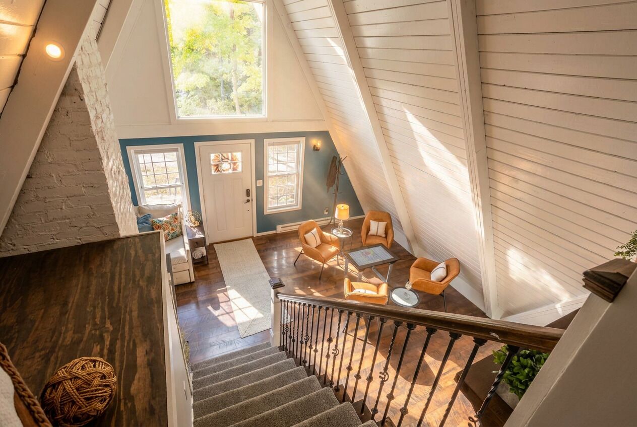 Un loft spacieux avec un plafond haut, un escalier et un coin salon comprenant une table et des chaises.