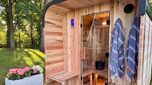 Una sauna de madera con puerta de vidrio, un banco y toallas colgadas en la pared.