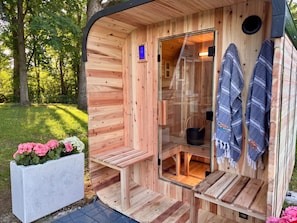 Una sauna de madera con puerta de vidrio, un banco y toallas colgadas en la pared.
