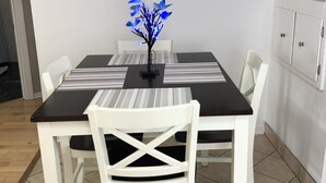 Un comedor con una mesa, sillas y un centro de mesa decorativo con flores azules.