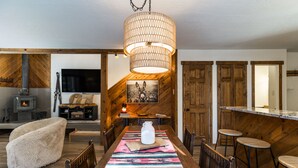 Un coin repas chaleureux avec une table en bois, un grand luminaire en fibres tressées et une décoration rustique.