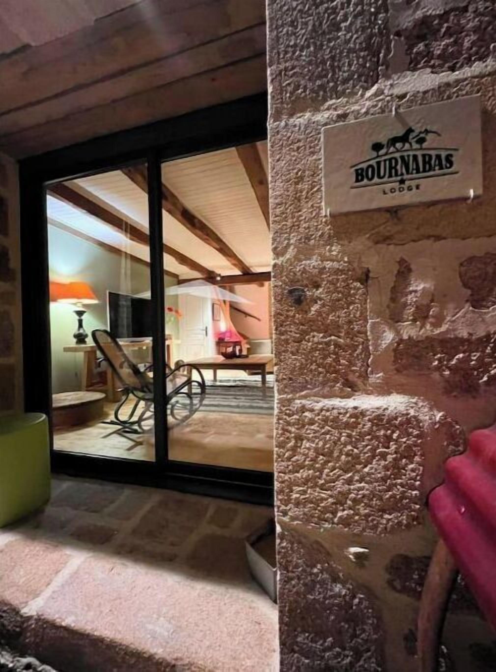 A rustic interior with a stone wall and a sign reading "BOURNABAS LODGE".