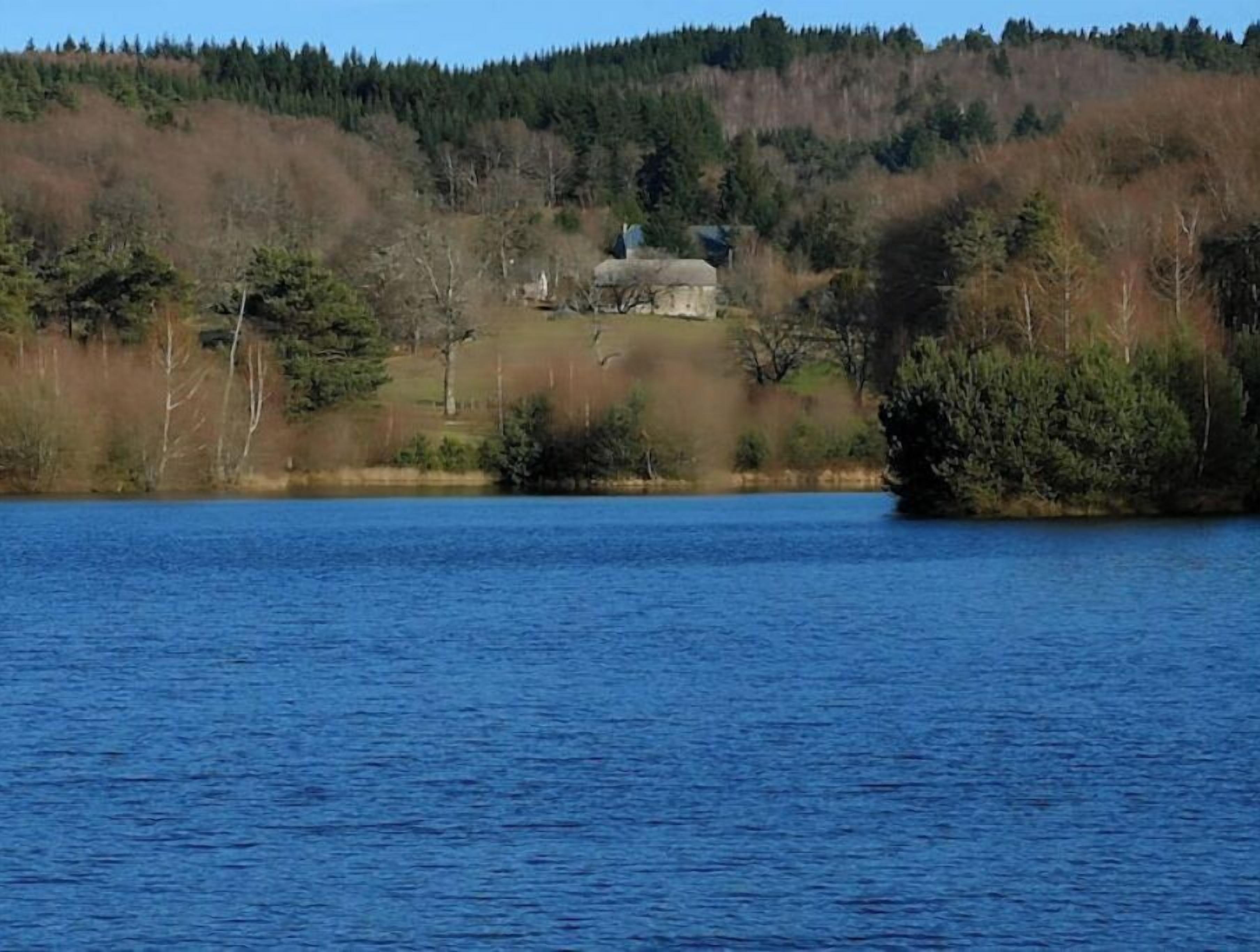 A lake with a house on a hill in the background.