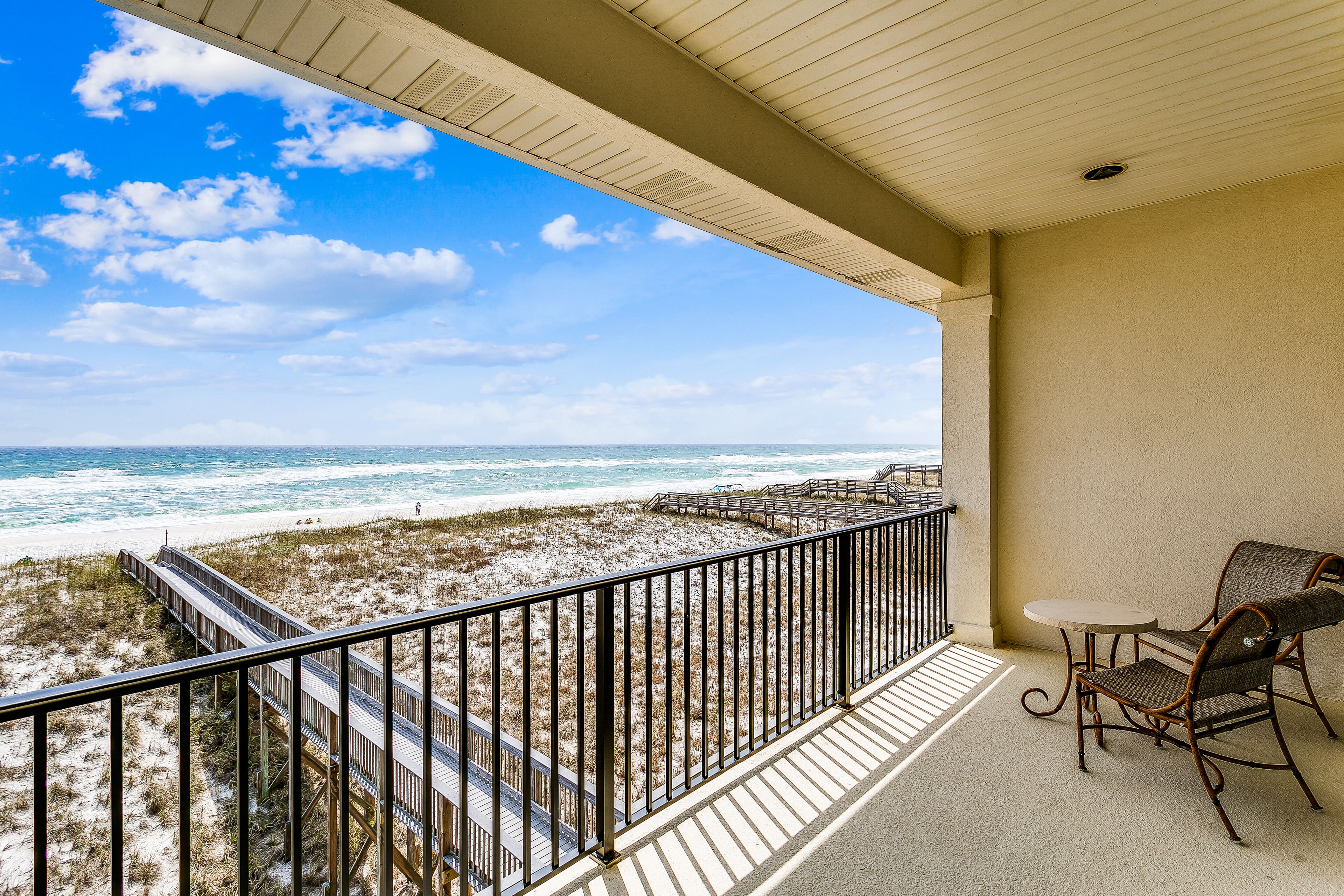 A balcony with a view of the beach and ocean.
