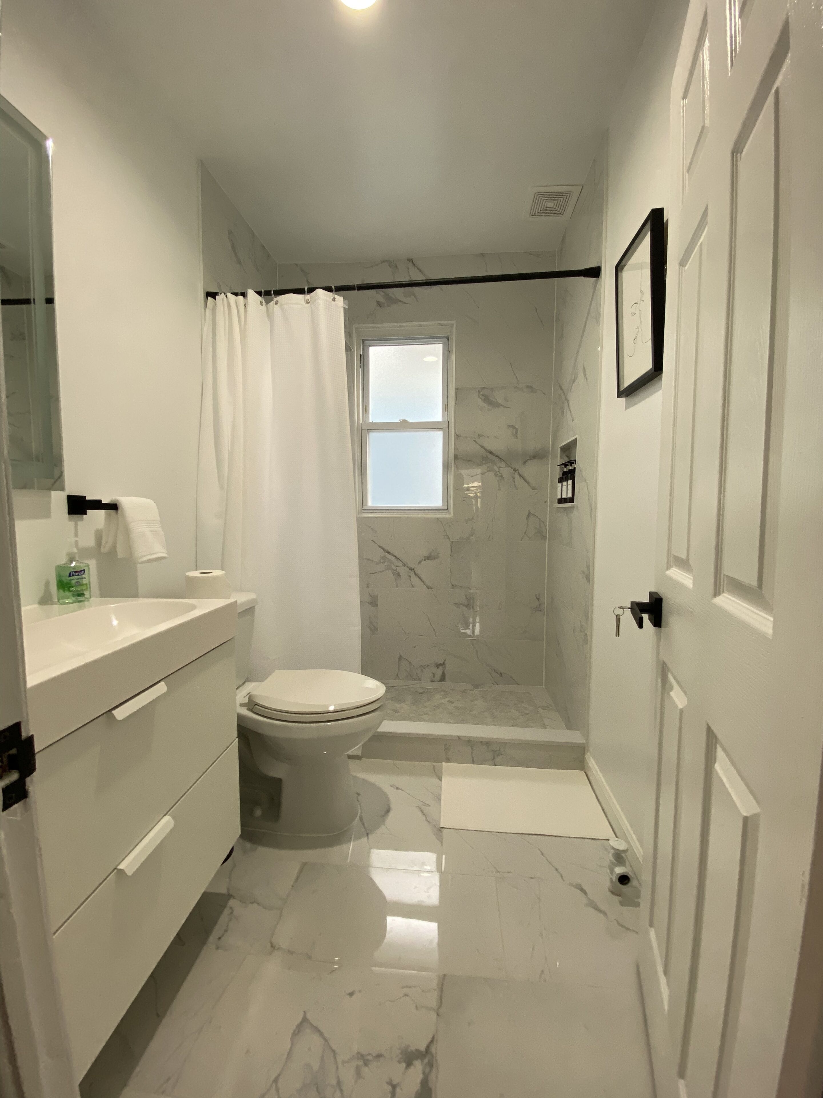 A bathroom with a toilet, a shower, and a sink.