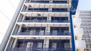 Un edificio de varios pisos con un diseño arquitectónico moderno, que cuenta con balcones y ventanas amplias.