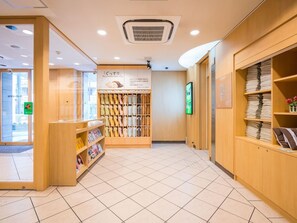 A bookstore with shelves of books and magazines, a display of folded clothes, and a sign with Japanese text. - Super Hotel Osaka Chikatesu Tanimachi-4chome (Osaka)