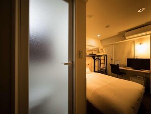 A hotel room with a bed, a desk, a chair, a TV, and a bunk bed in the background. - Super Hotel Osaka Chikatesu Tanimachi-4chome (Osaka)