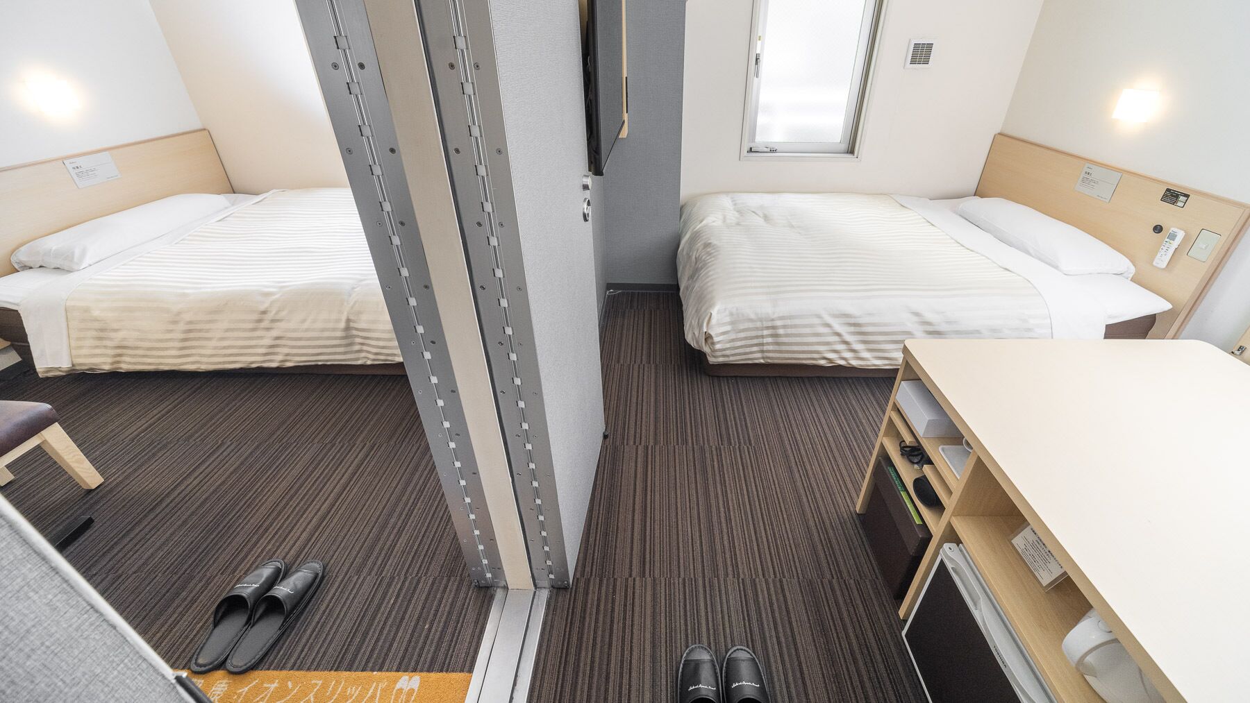 A hotel room with two beds, a desk, and a chair.