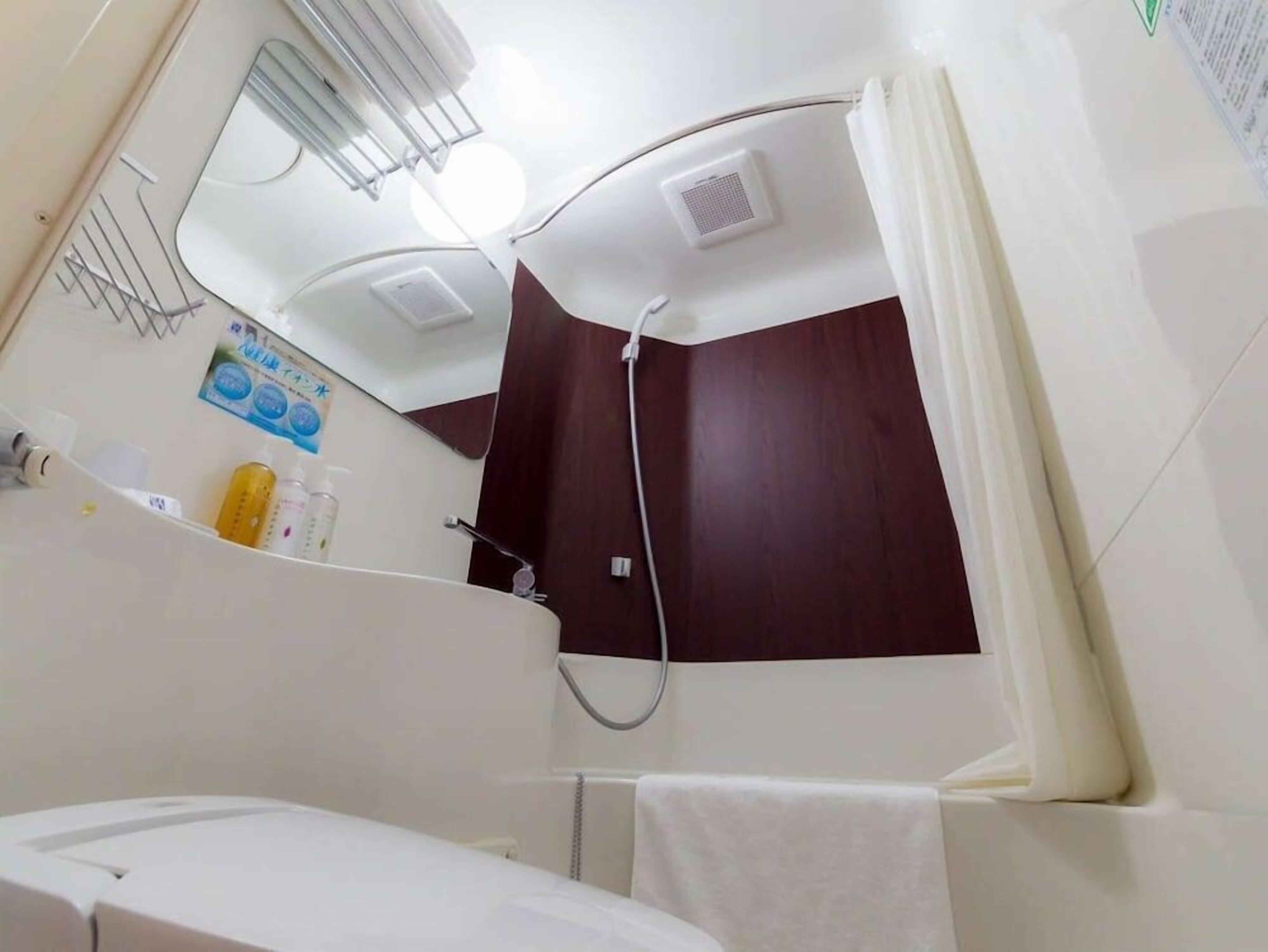 A bathroom with a shower, a mirror, and a towel rack.