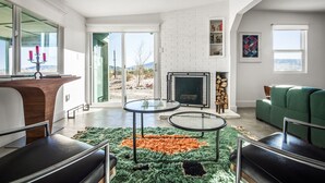 Una sala de estar moderna con chimenea, un sofá verde y una mesa de centro de vidrio.