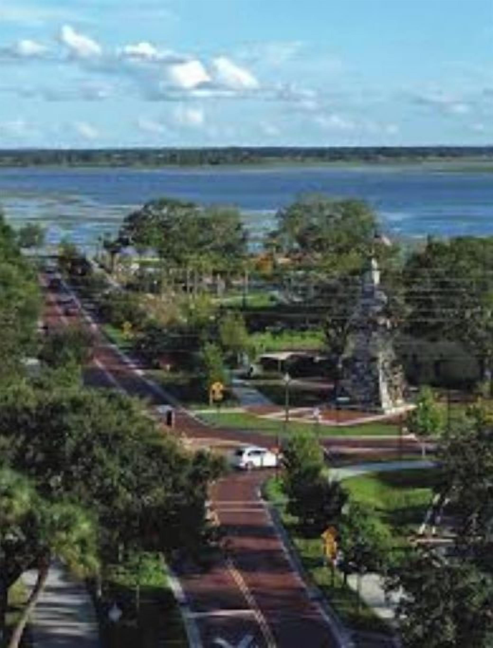 A coastal road with a park area, a statue, and a view of the sea.