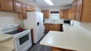 Una cocina con armarios de madera, un refrigerador blanco, una estufa y un microondas.