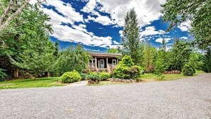 A house with a gravel driveway, surrounded by trees and a clear sky. - Tatum’s Retreat -SAUNA- Hiking-Wineries- Unit B (Madison)